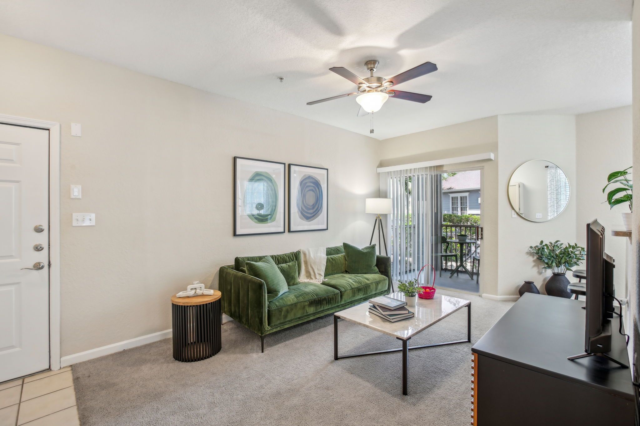 A stylish living room featuring a green sofa, coffee table, and balcony access.