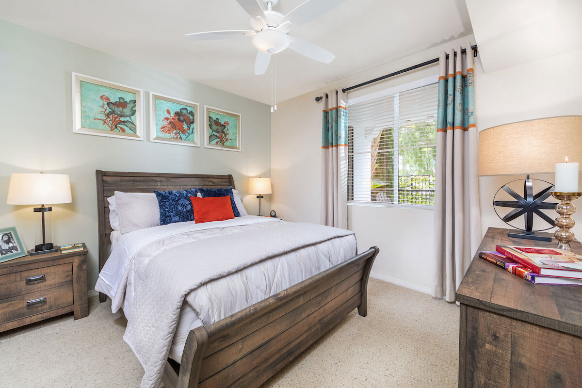 Bedroom with a bed, decorative pillows, and a fan.