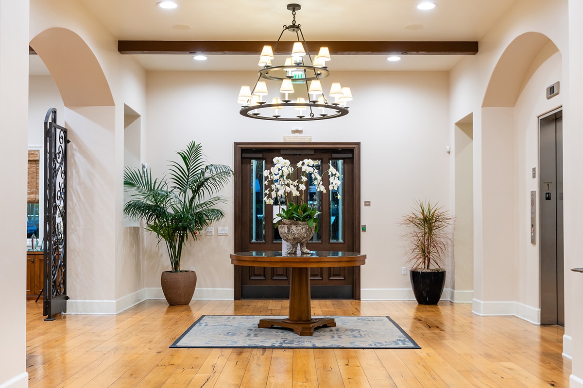 Lobby with chandelier, plants, and welcoming table.