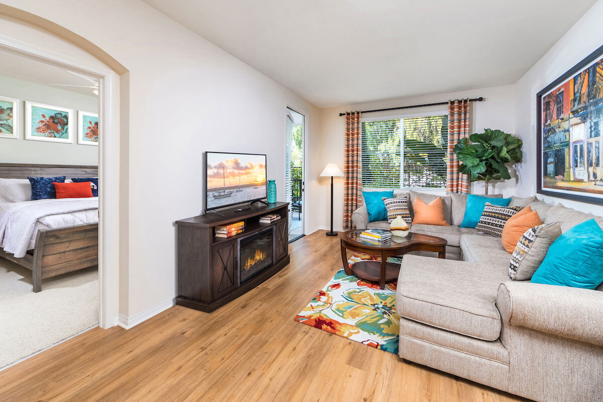 Cozy living room with a sectional couch, TV, and a view of a bedroom.
