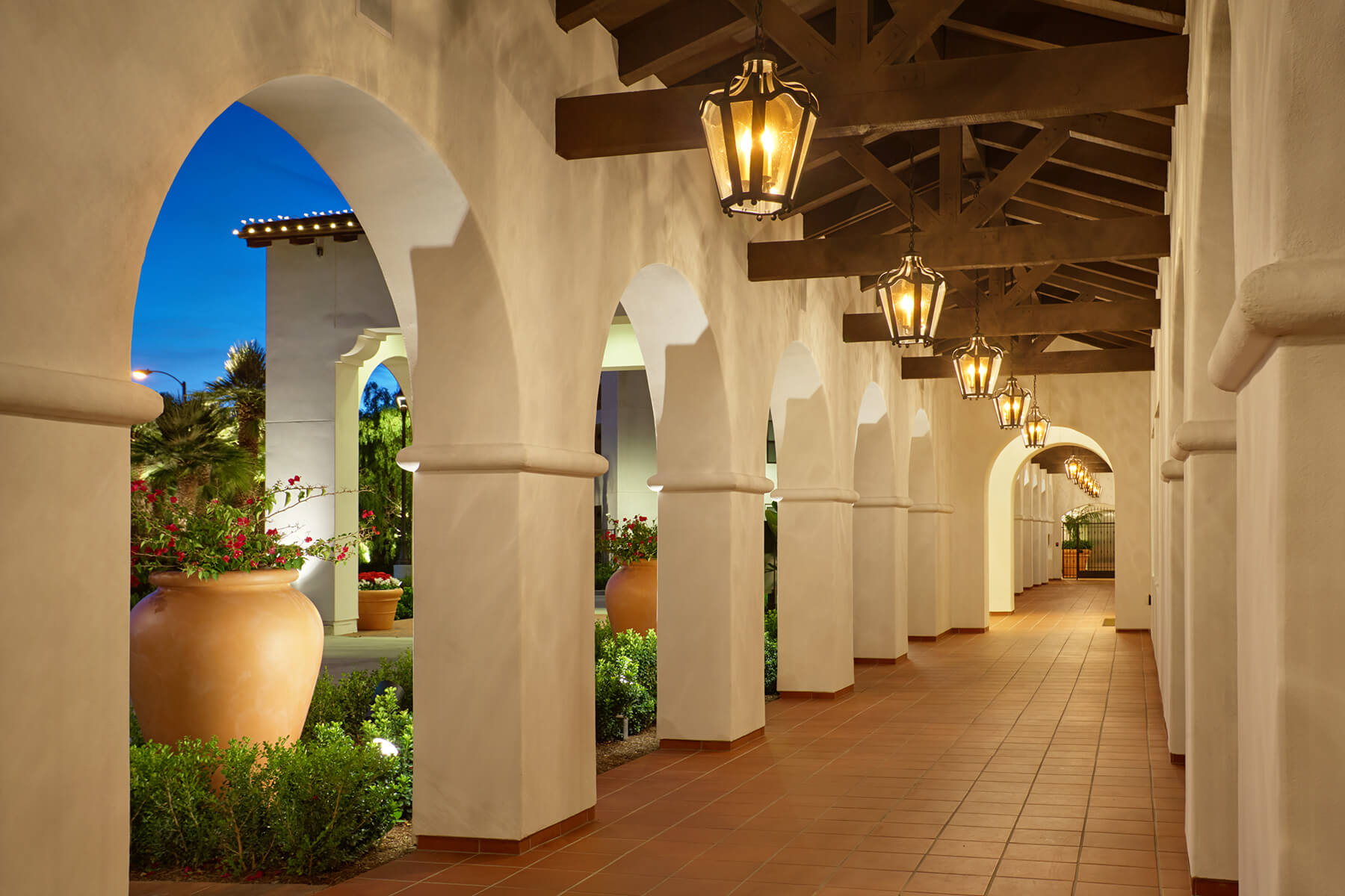 Outdoor corridor with arches and greenery.