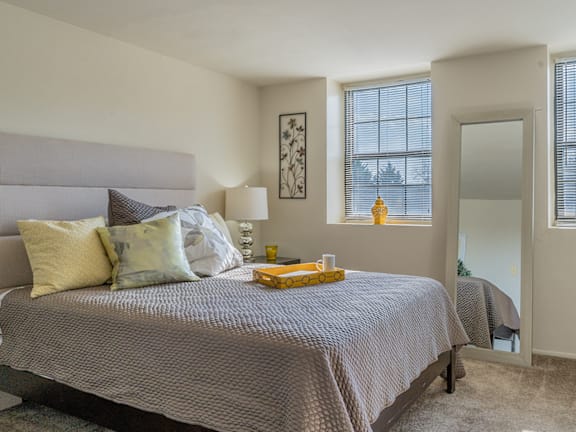 A bedroom with a large bed and a mirror on the wall at Dutch Village Apartments, Baltimore, MD