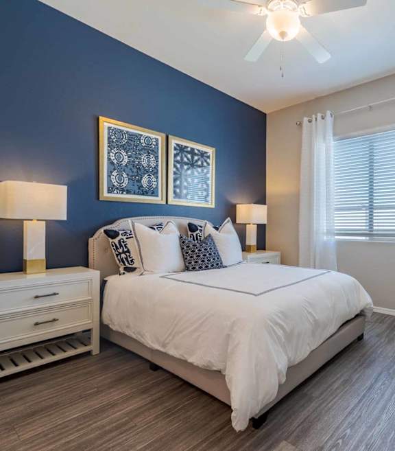 Modern bedroom with blue accent wall at Vistoria On Mountain View Apartments, Surprise