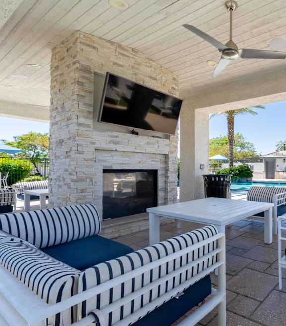 Covered patio with fireplace and pool at Vistoria On Mountain View Apartments, Surprise, Arizona