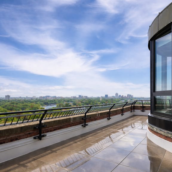 A balcony with a glass door overlooks a cityscape.