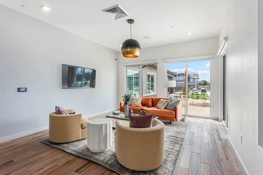 Apartment living area with plush seating, pattern rug, wall mounted TV, and elegant light fixture.