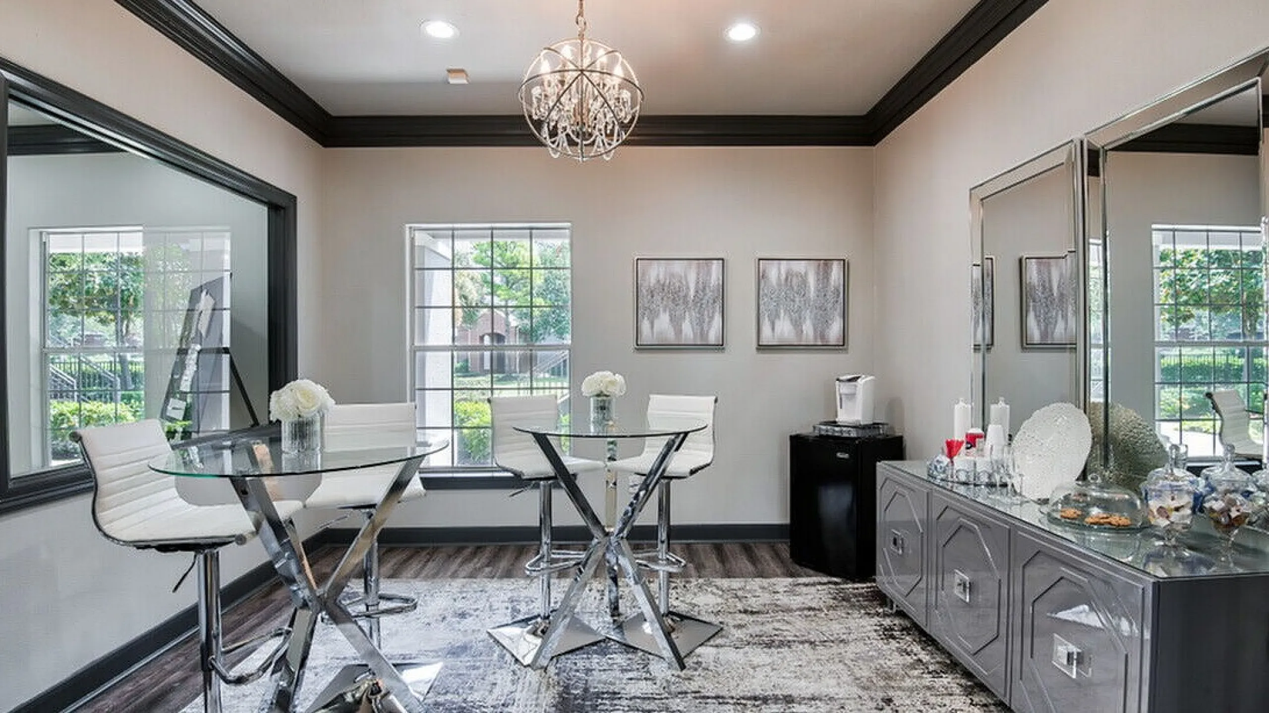Modern dining area with chic glass table, elegant chandelier, and large windows offering abundant natural light.