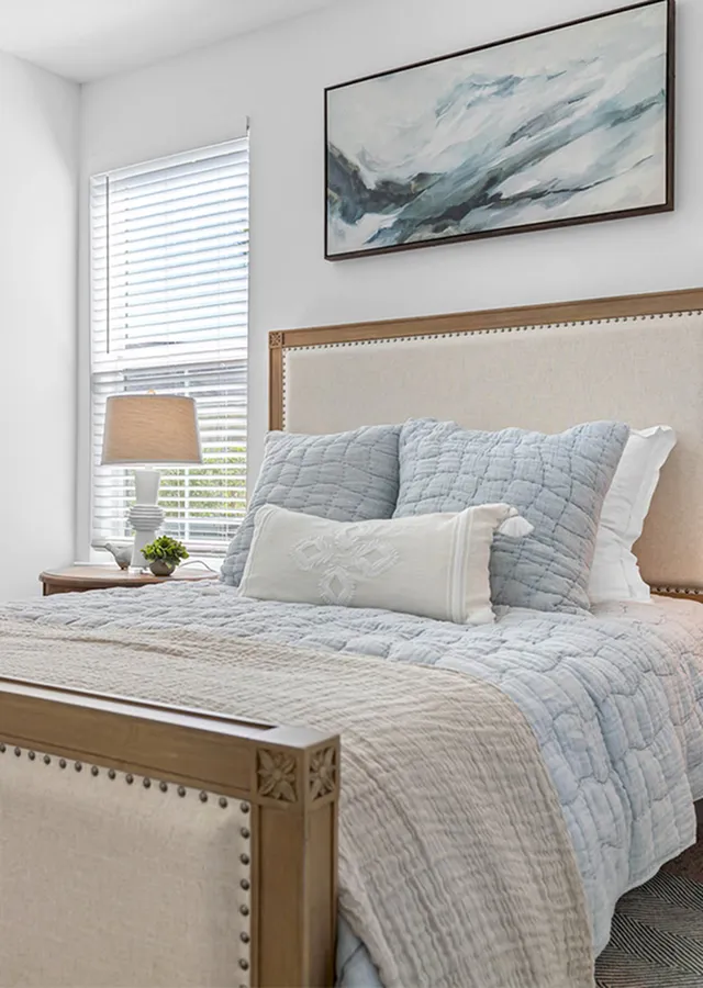 Serene bedroom with elegant decor, featuring a cozy bed with pastel linens and a large window inviting natural light.