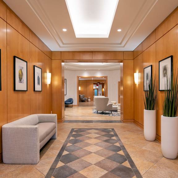 A hallway with a bench, a rug, and framed pictures on the wall.