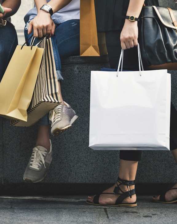 A woman is holding a shopping bag and smiling at the camera.