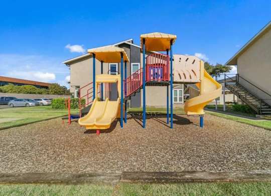 A playground with a yellow slide and a red and yellow climbing structure.