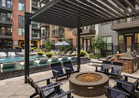 A patio with a fire pit and chairs.
