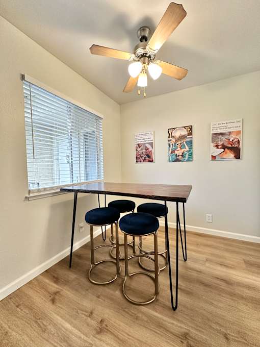 a dining room with a table and four stools under a ceiling fan