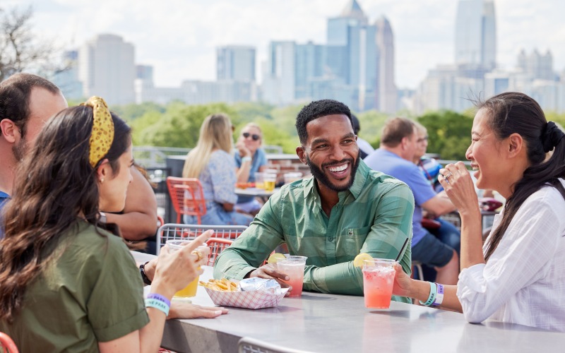 Flats at Ponce City Market residents sitting together on a rooftop with the Atlanta skyline behind them