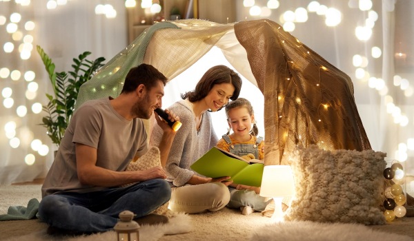 family sitting under a lit tent