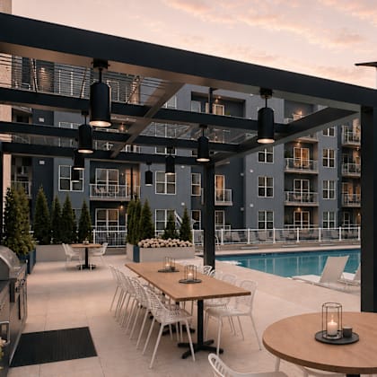 A modern outdoor dining area with tables and chairs is set up next to a pool.