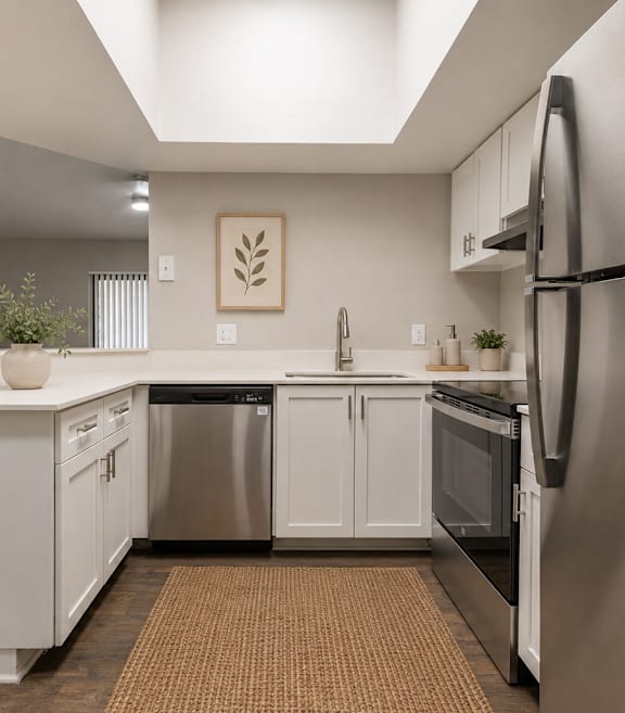 A modern kitchen with white cabinets and stainless steel appliances.