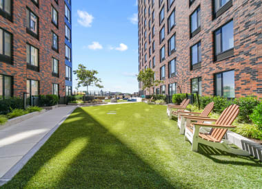 a courtyard with chairs and grass in front of a brick building
