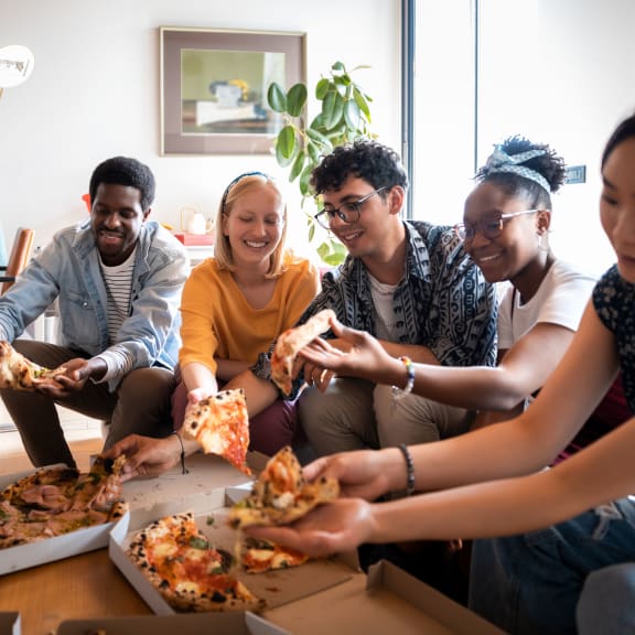 a group of people sitting around a table eating pizza