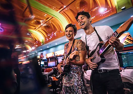 couple playing guitar hero style game at an arcade