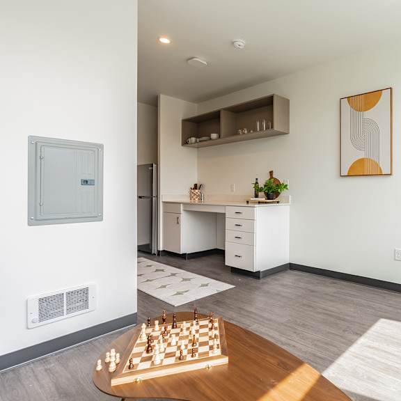 A kitchen with a stool, a fridge and a counter.