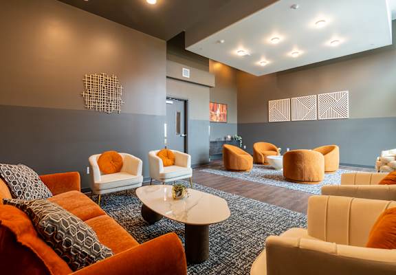 A room with orange and white chairs and a black coffee table.