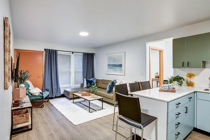 Inviting modern living room with a cozy beige sectional sofa, chic coffee table, and stylishly decorated open kitchen.