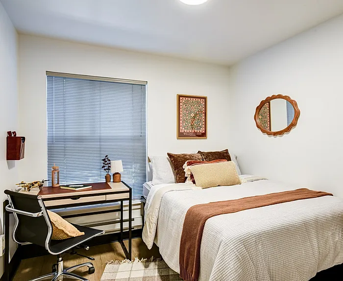 Cozy and stylish bedroom with modern desk and plush bedding, perfect for comfort and productivity.