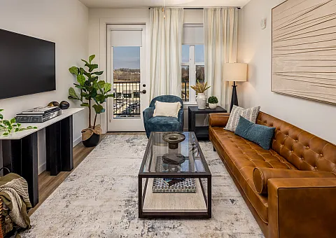 Modern living room with a stylish leather sofa, elegant decor, and natural light streaming through large windows, creating an inviting and cozy atmosphere.