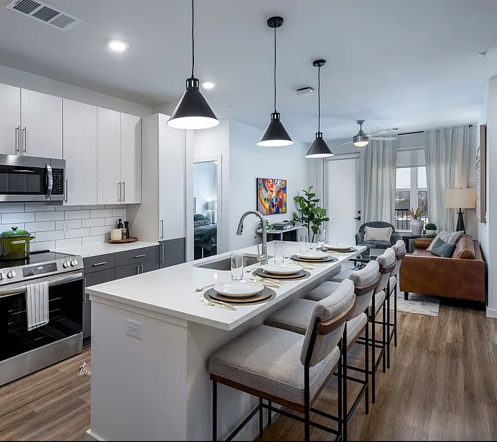 Modern open-concept kitchen and living area with sleek appliances, elegant lighting, and a cozy seating arrangement.