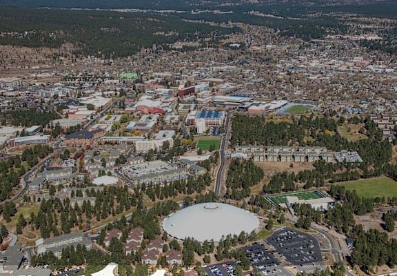 A large white dome structure is surrounded by buildings in a city.