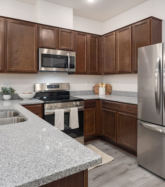 A kitchen with brown cabinets and a granite counter.