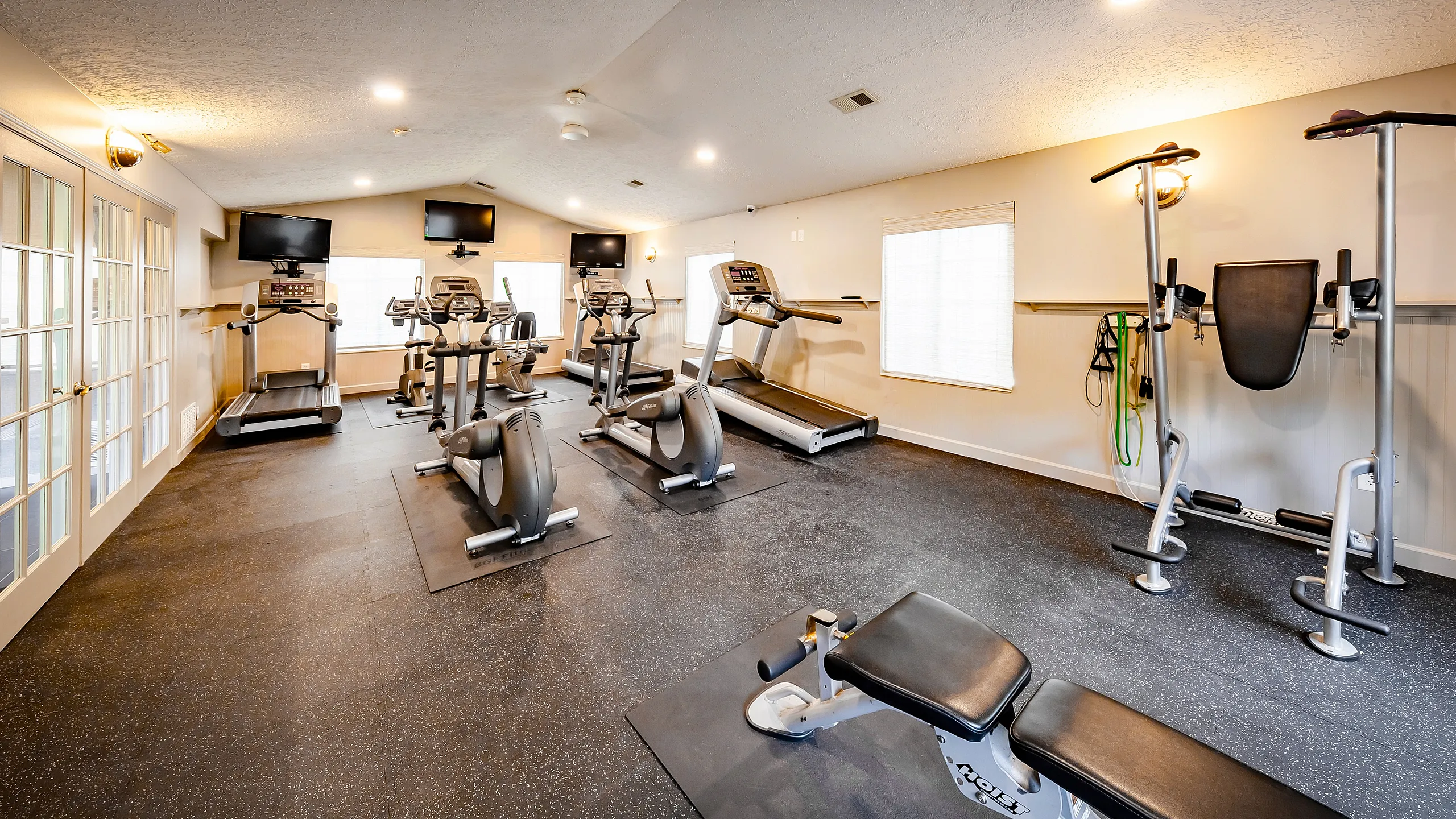 State-of-the-art fitness center with modern cardio equipment, weight machines, and ample natural light for an invigorating workout experience.