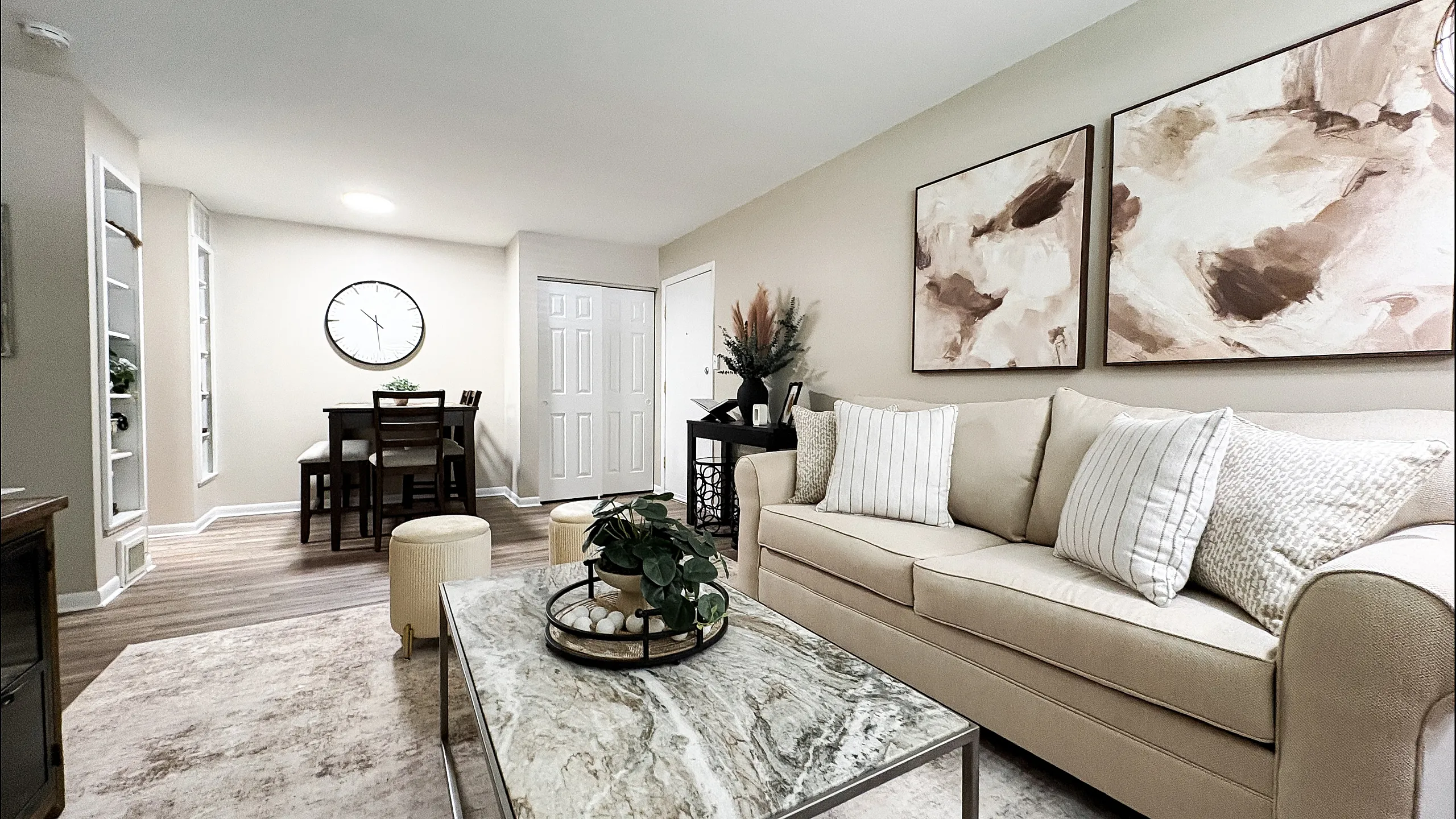 Inviting living area with elegant beige sofa, stylish artwork, and modern dining space, featuring a chic marble coffee table and tasteful decor.