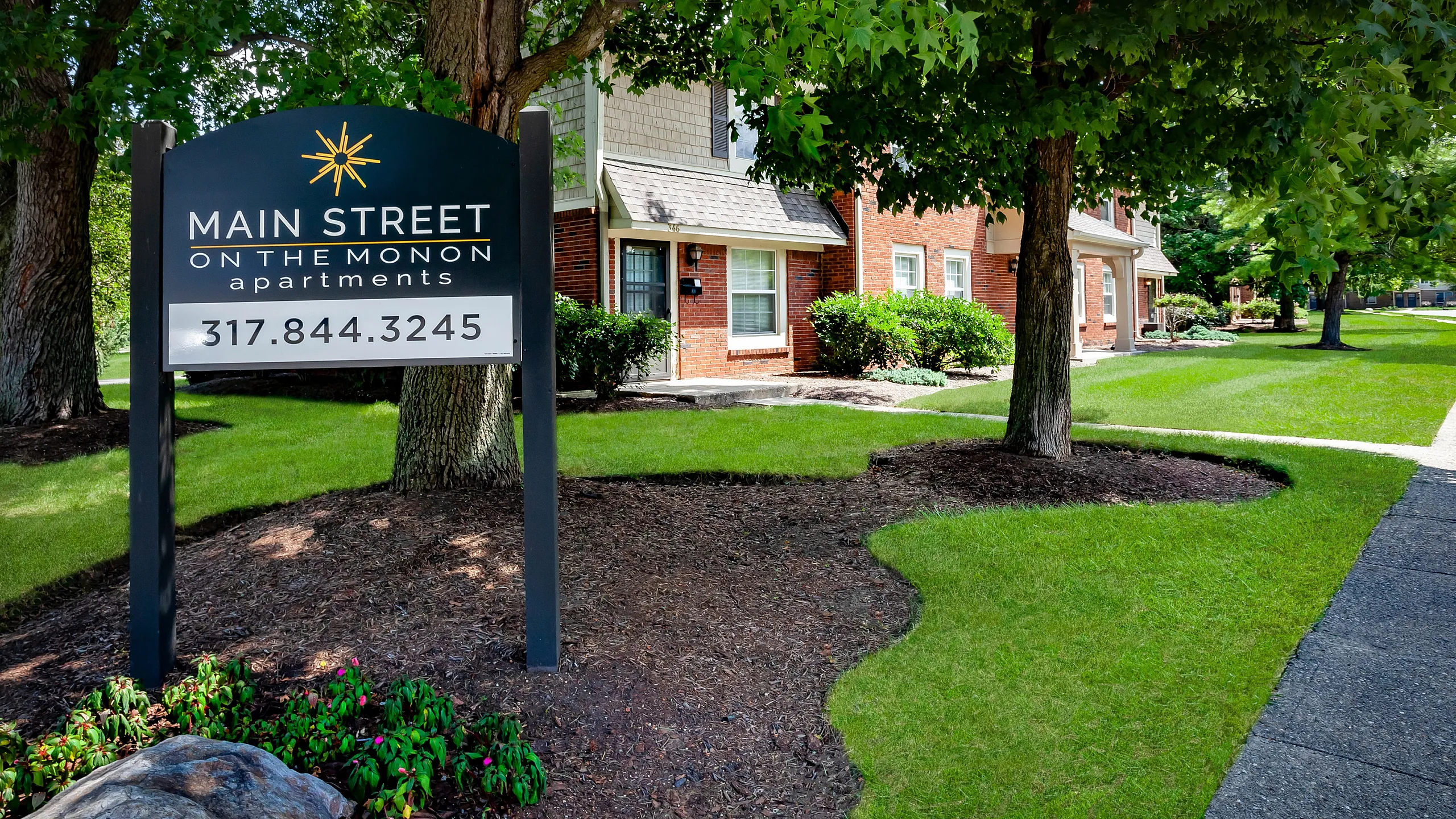 Charming apartment community with lush greenery and inviting facade at Main Street on the Monon.