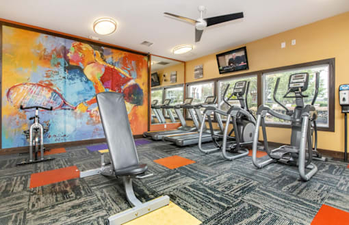A gym with a row of treadmills and a row of stationary bikes.