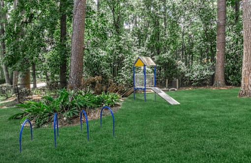 A playground with a swing set and a slide in a park.