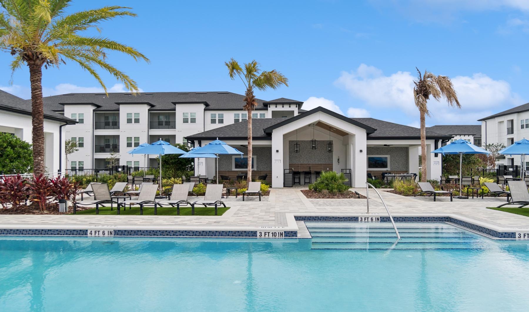 a pool with chairs and umbrellas by a building