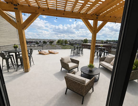 A patio with a wooden pergola and wicker furniture.