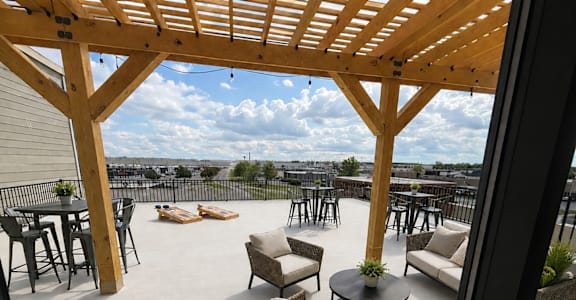 A patio with a wooden pergola and wicker furniture.