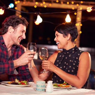Resident couple clinking glasses at a restaurant near Sofi Westview in San Diego, California