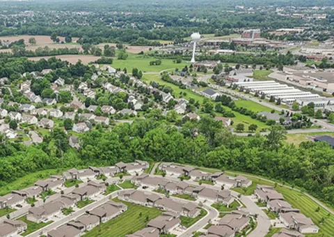 Scenic aerial view showcasing a picturesque residential community surrounded by lush greenery and distant landscapes.