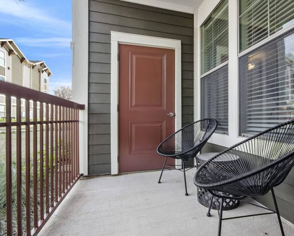 a porch with two chairs and a red door