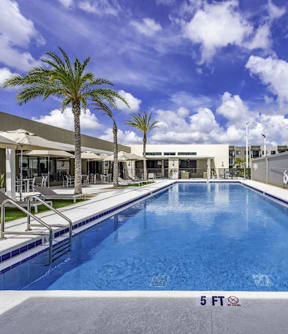 a swimming pool with lounge chairs and umbrellas in front of a brick building