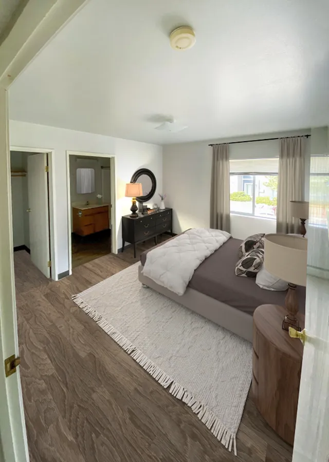 Bright and inviting bedroom with modern decor, featuring hardwood floors, a large window, and an ensuite bathroom.