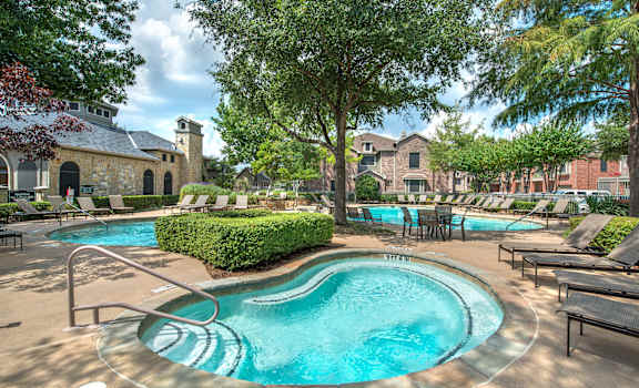 A large outdoor swimming pool surrounded by lounge chairs and trees.