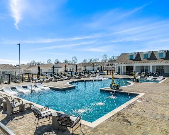 A large outdoor swimming pool with a fountain in the middle and lounge chairs around it at Ovation at Town Madison, Madison, 35758