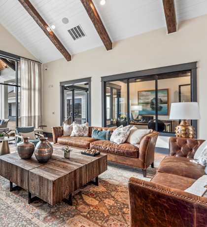 A living room with a brown leather couch and a wooden coffee table. at Ovation at Town Madison, Madison, Alabama