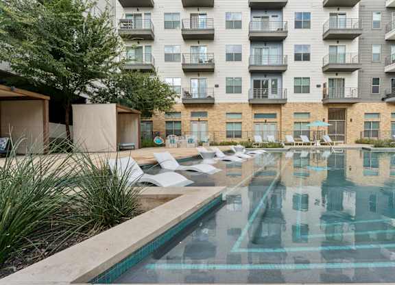 A large swimming pool in front of apartment buildings.