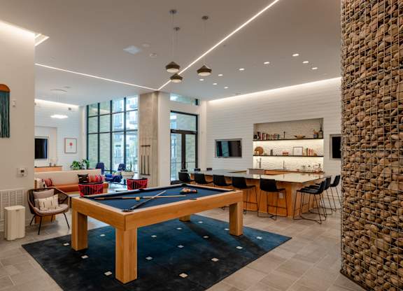 A room with a pool table and a stone pillar.